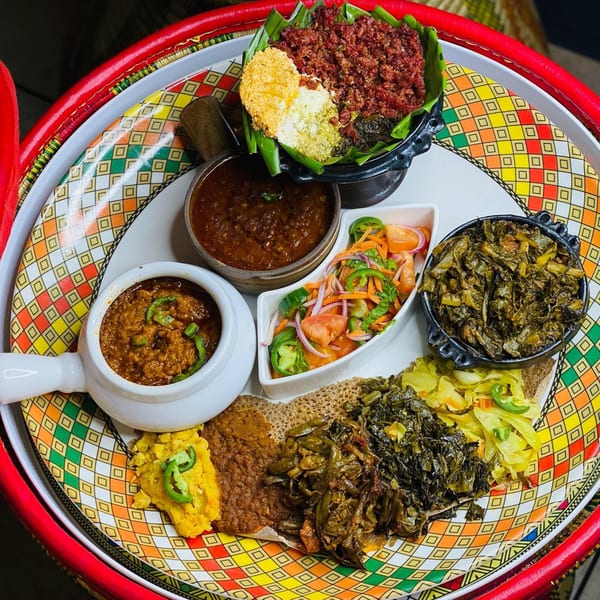 A colorful platter of various Ethiopian dishes, including stews, vegetables, and injera bread.