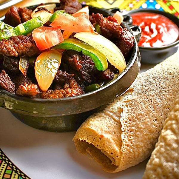 Ethiopian Tibs, a meat dish with vegetables, injera bread, and a red sauce.